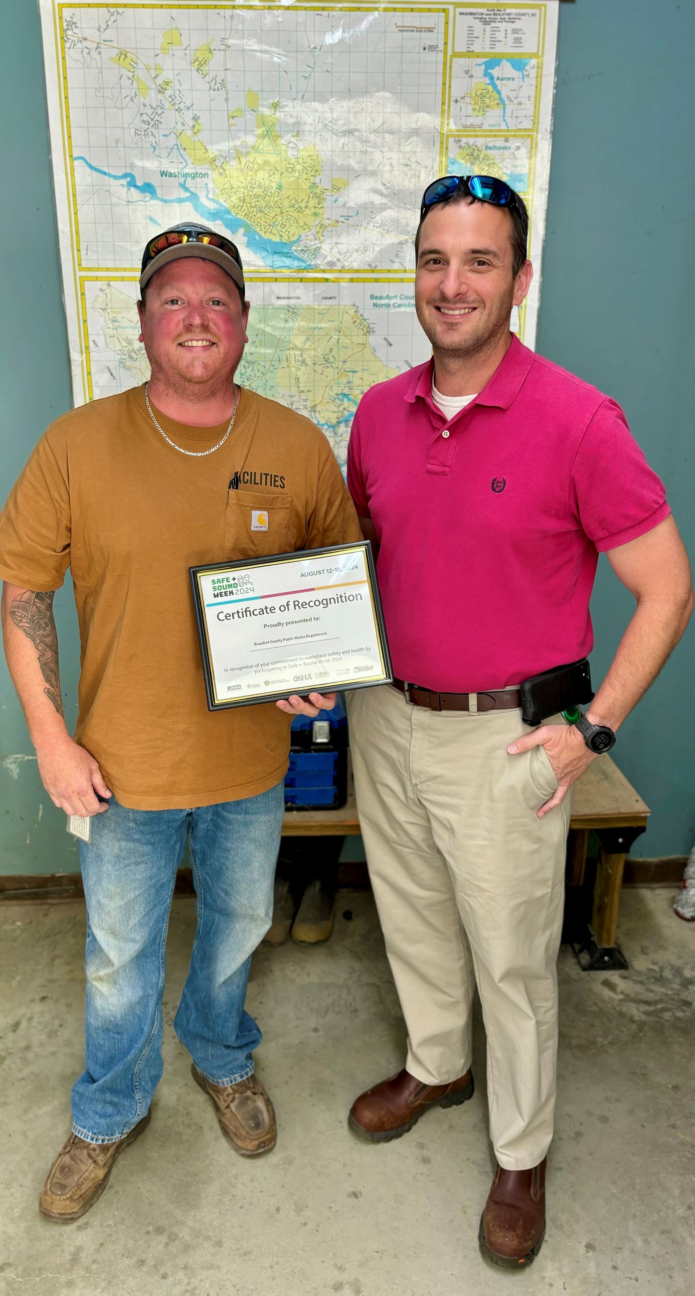 Two employees holding a certificate
