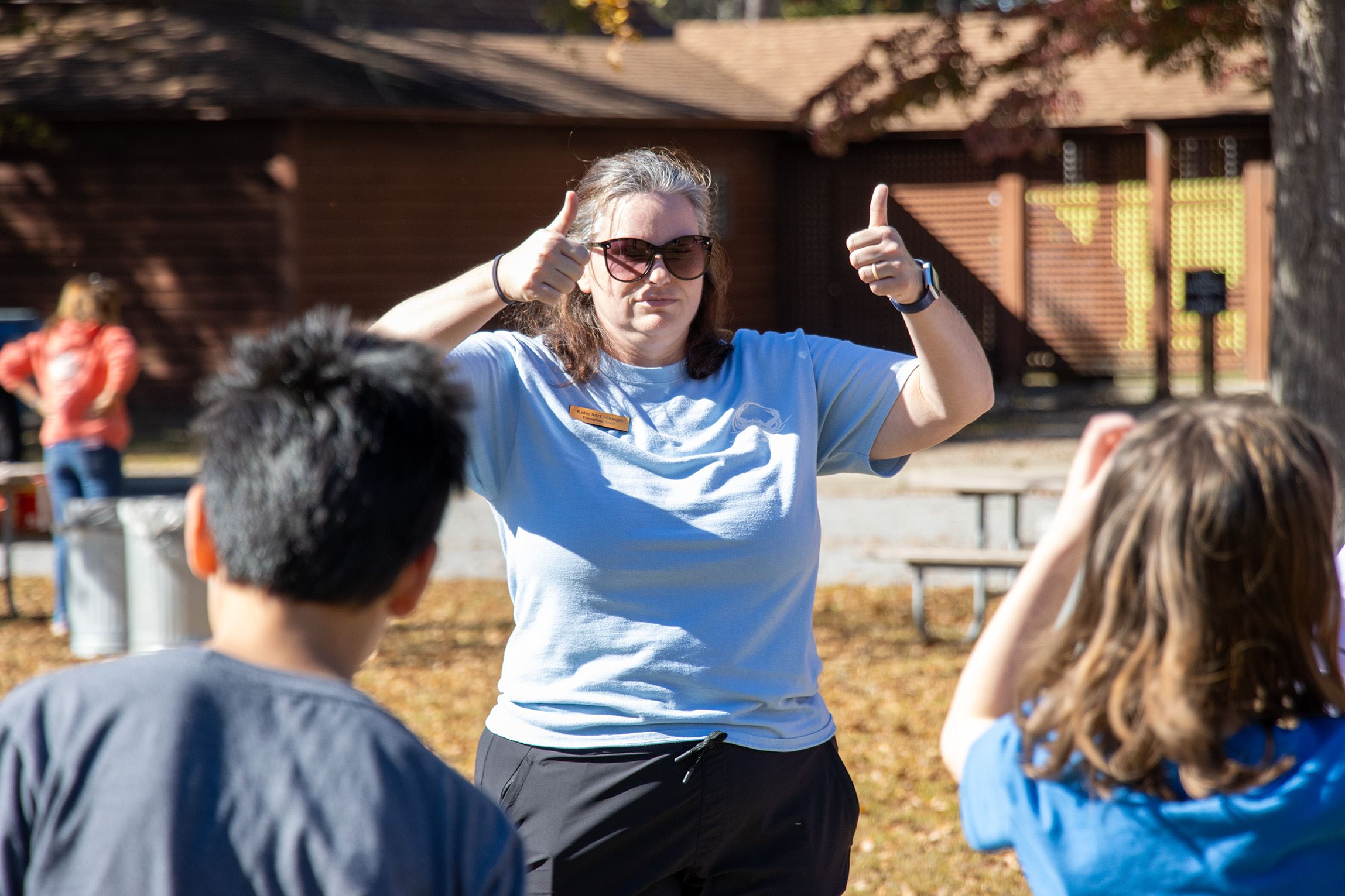 A female instructor giving two thumbs up to a group of students while explaining an activity at Environmental Field Days