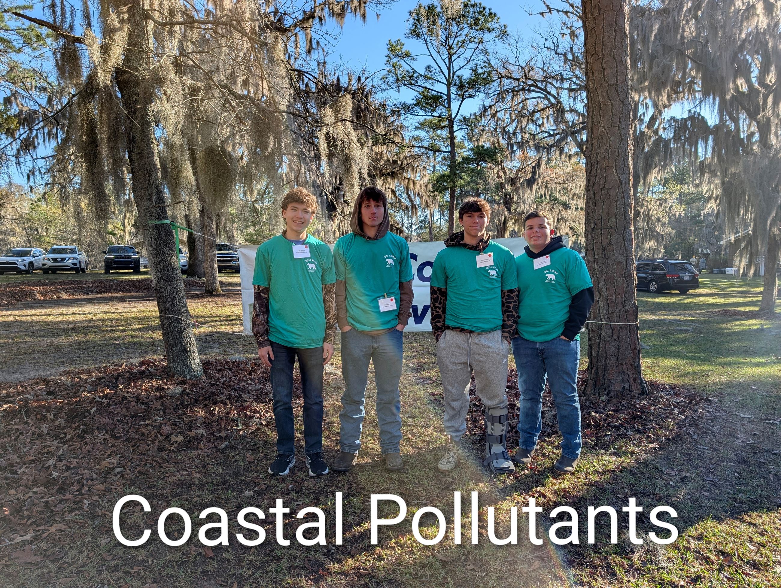 Four students standing together in a wooded area